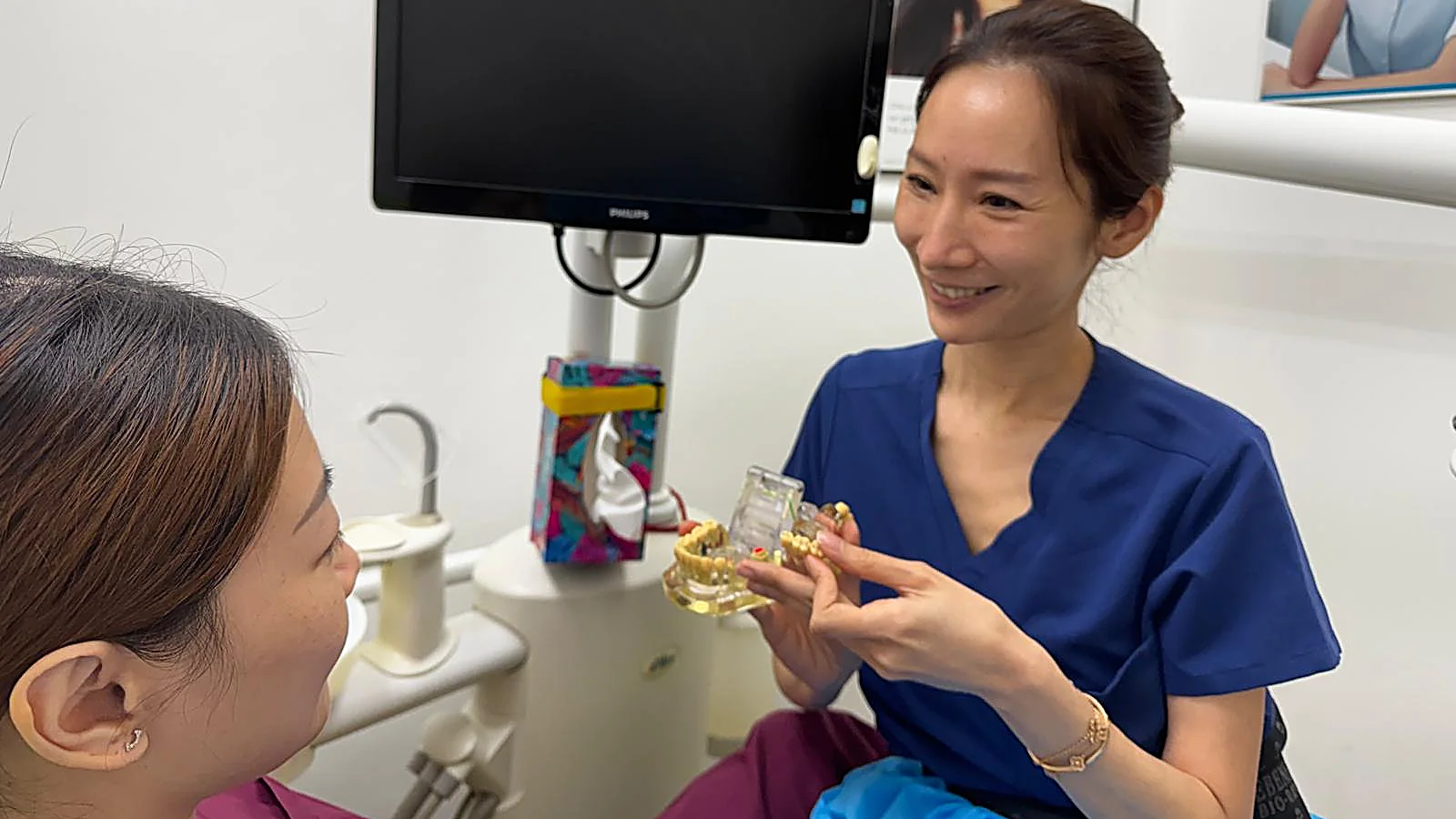A Caring Dental dentist showing a patient how crowns and bridges restore missing teeth using a dental model