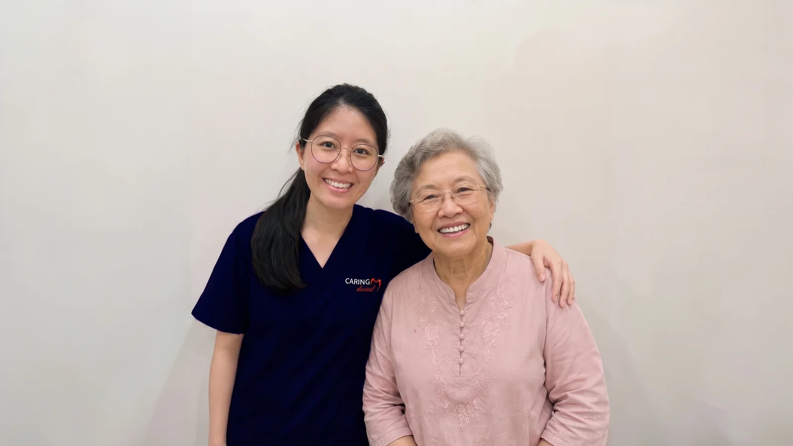 A smiling senior patient with her Caring Dental dentist after a denture fitting