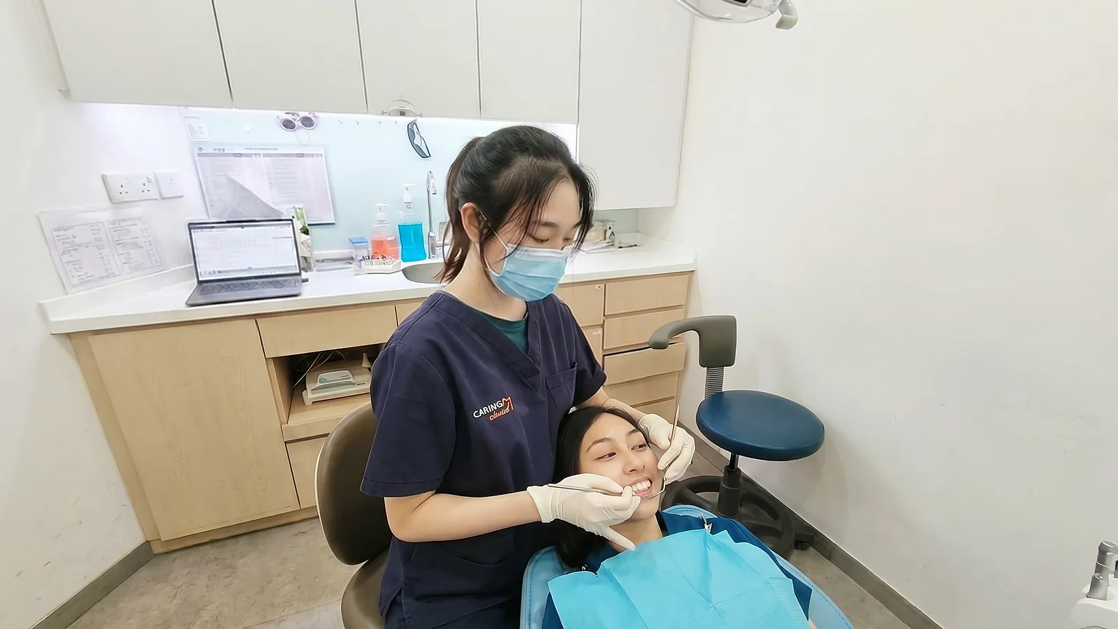 A Caring Dental dentist examining a smiling patient in the dental chair before a filling