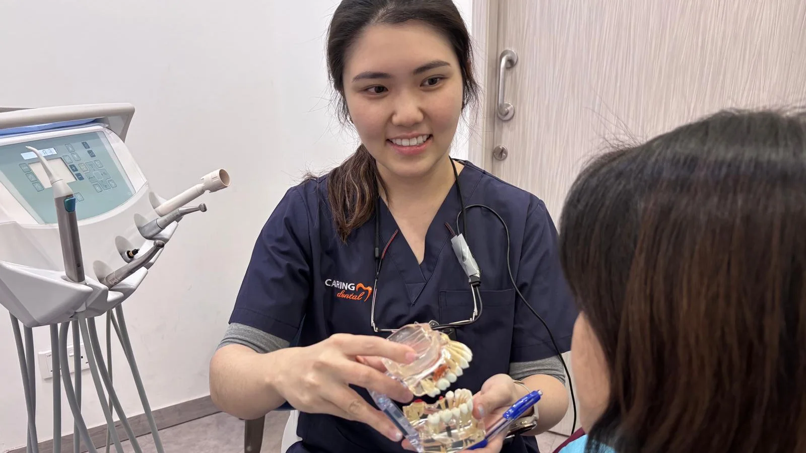 A Caring Dental dentist explaining dental implants to a patient with a clear dental implant model