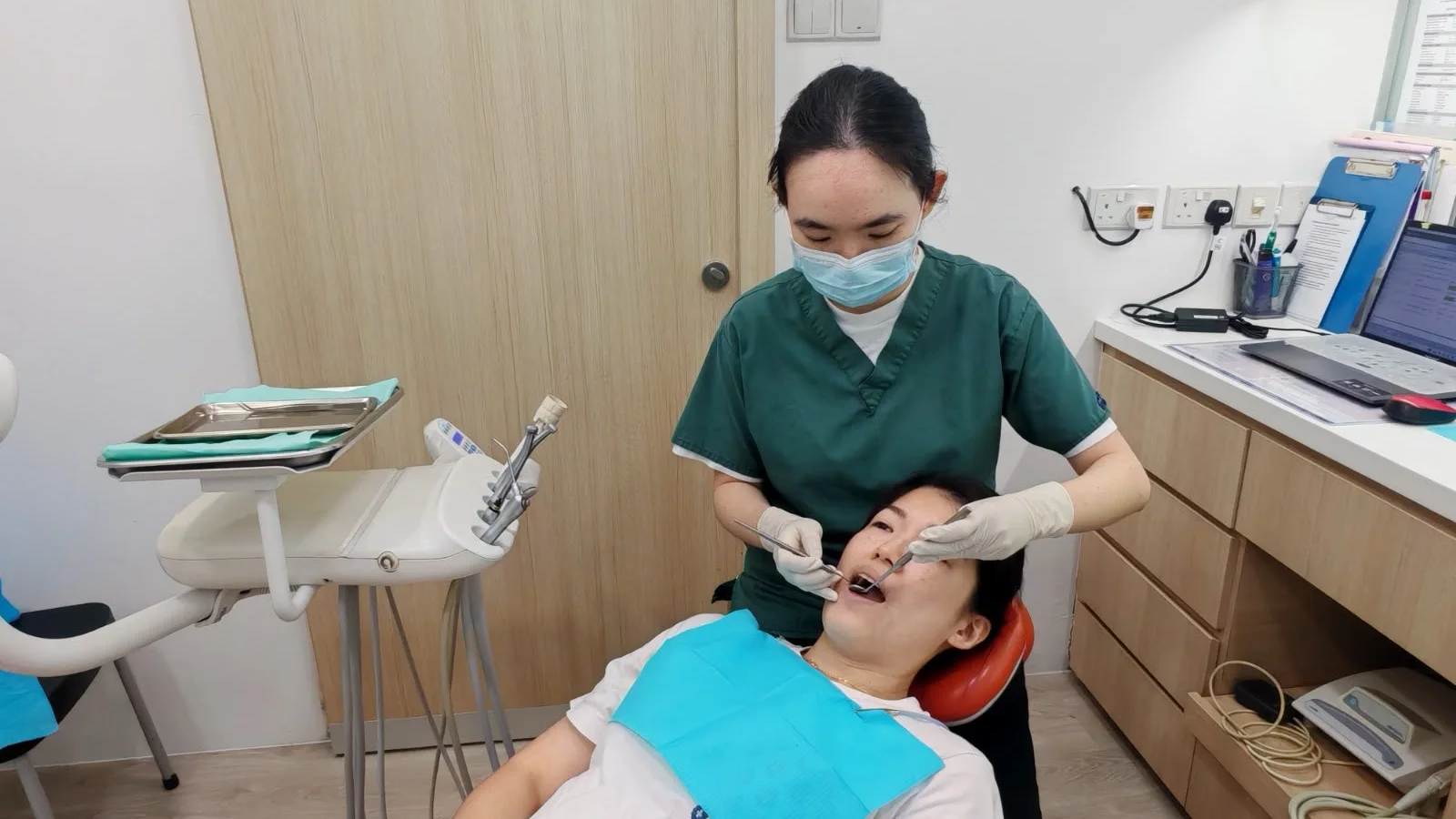 A Caring Dental dentist performing scaling and polishing for a patient in the dental chair