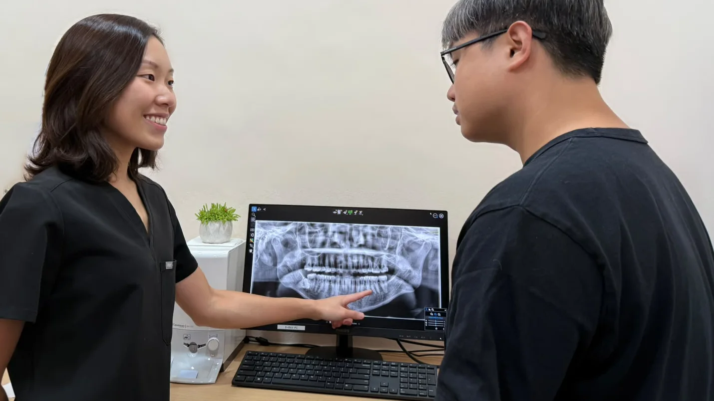 A Caring Dental dentist pointing out details on a panoramic dental X-ray while explaining the results to a patient